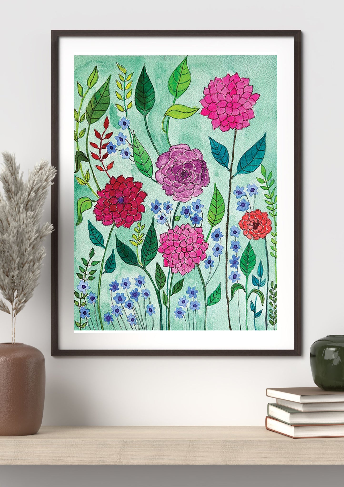 Framed floral art print featuring watercolor-style pink, red, blue, and green flowers on a mint background, displayed on a shelf with decorative vases and books.